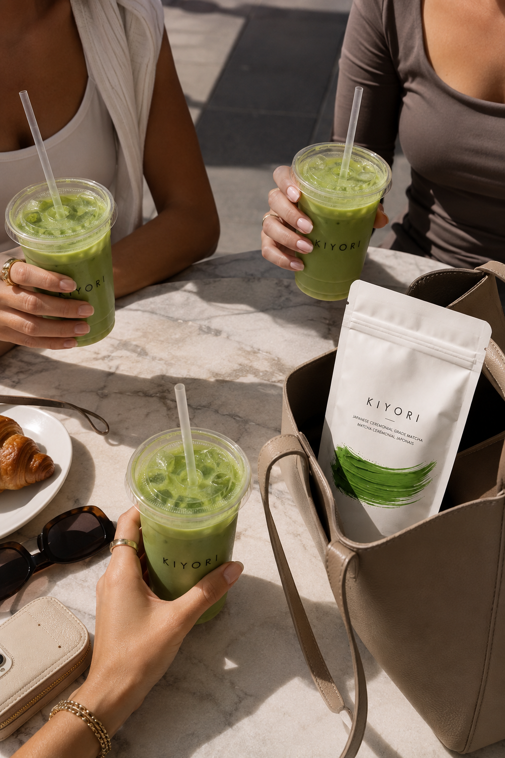 Friends sharing iced Kiyori matcha at a sunlit cafe with the ritual bag tucked into a tote