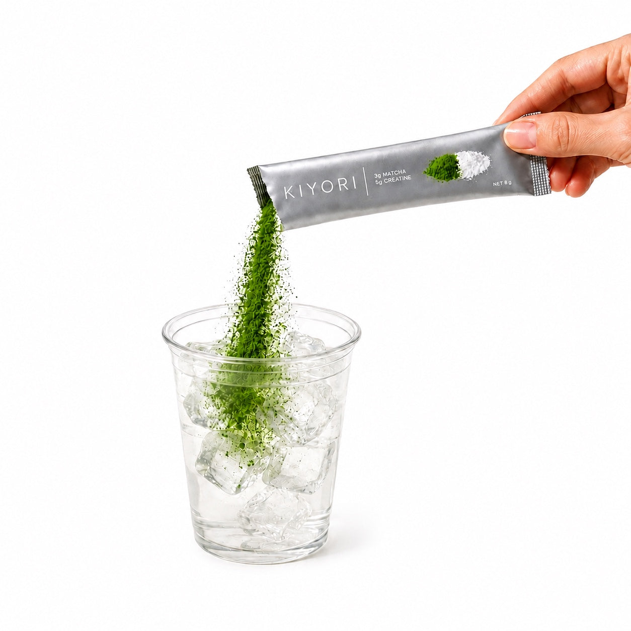 Torn silver Kiyori stick pouring matcha and creatine into an iced cup on white